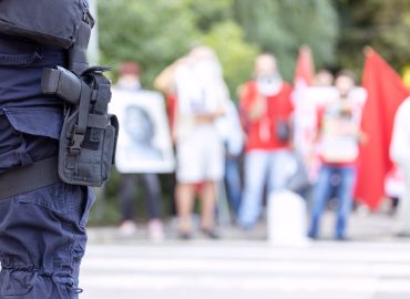 Policeman on duty during street protest, blurred protesters in the background